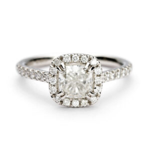 Platinum cushion halo engagement ring with a 1.01ct GIA round brilliant diamond and pavé-set diamond shoulders.
