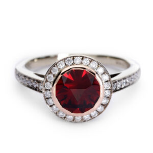 18ct gold garnet and diamond halo ring with a bespoke fantasy-cut garnet and milgrain-edged diamond halo.